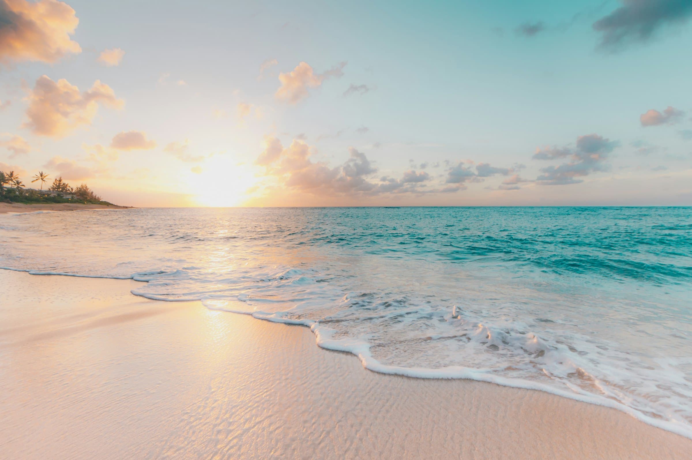 Sunrise over calm Gulf water and pale sand