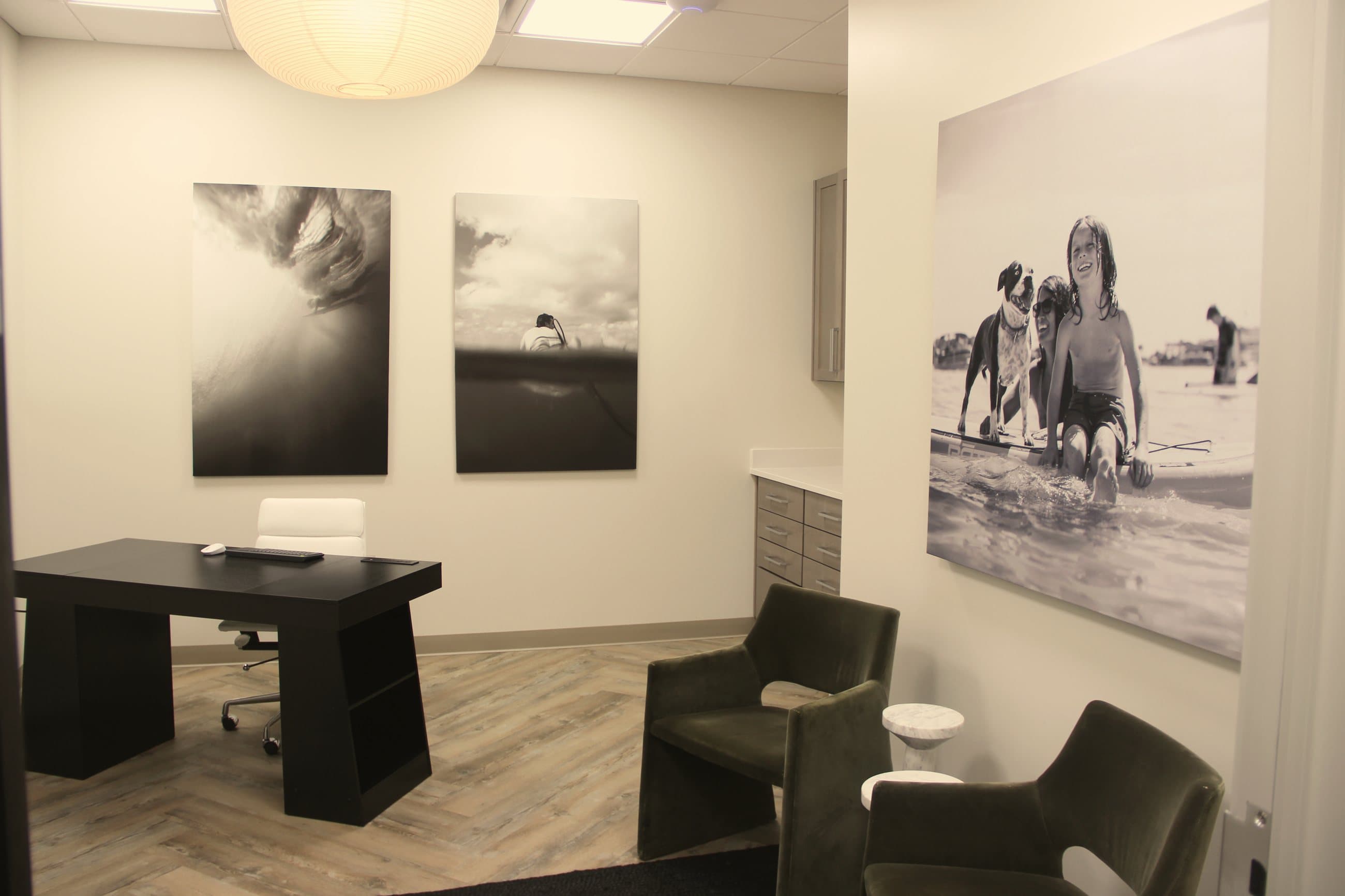 Office evaluation room with a desk, guest chairs, and coastal photographs